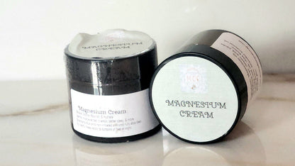 Two jars of Magnesium Cream on a light surface with a white background