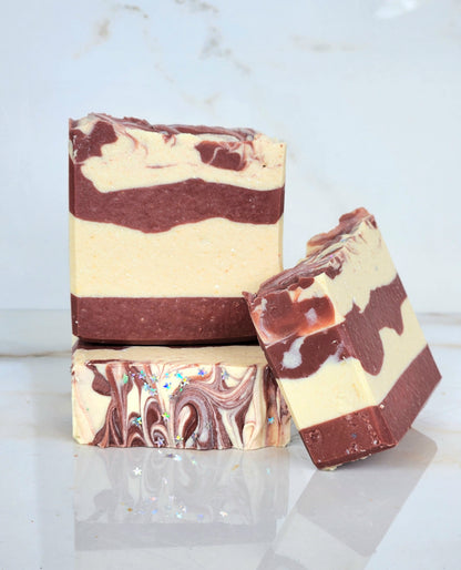 Three bars of red and white striped soap on a light marble background